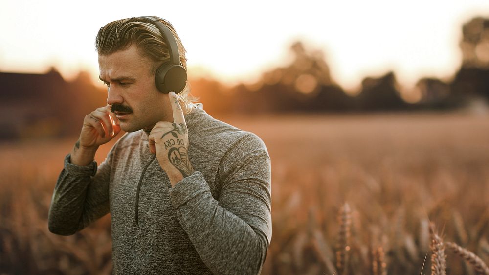Handsome man wearing wireless headphones in the countryside remixed media