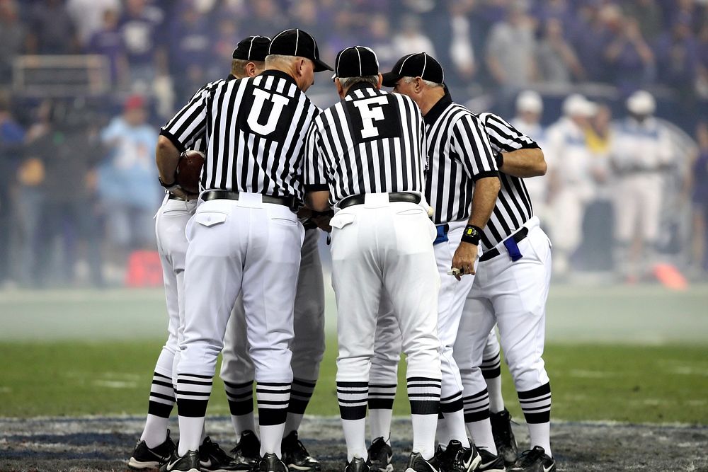 College football referees discussing, Texas Bowl, Houston, December 28, 2006. View public domain image source here