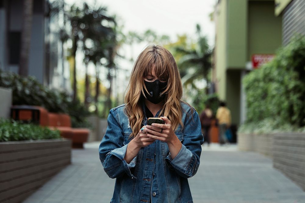 Woman with a face mask using a phone during coronavirus outbreak