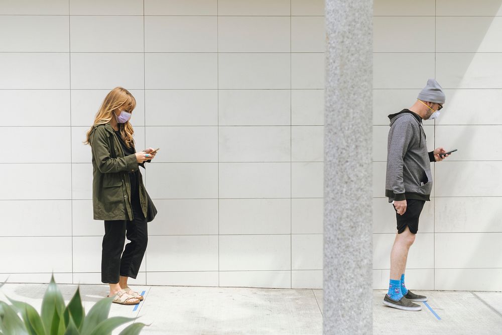 People using their phones and having social distancing while line up during coronavirus pandemic. Los Angeles, USA, April 4…