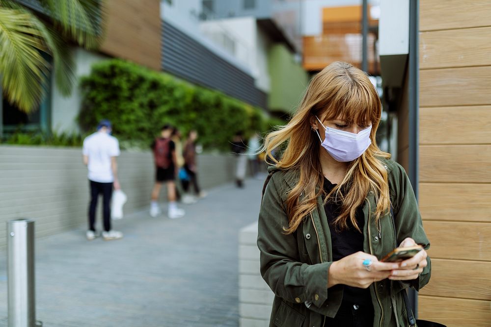 Woman with a face mask using a phone during coronavirus outbreak