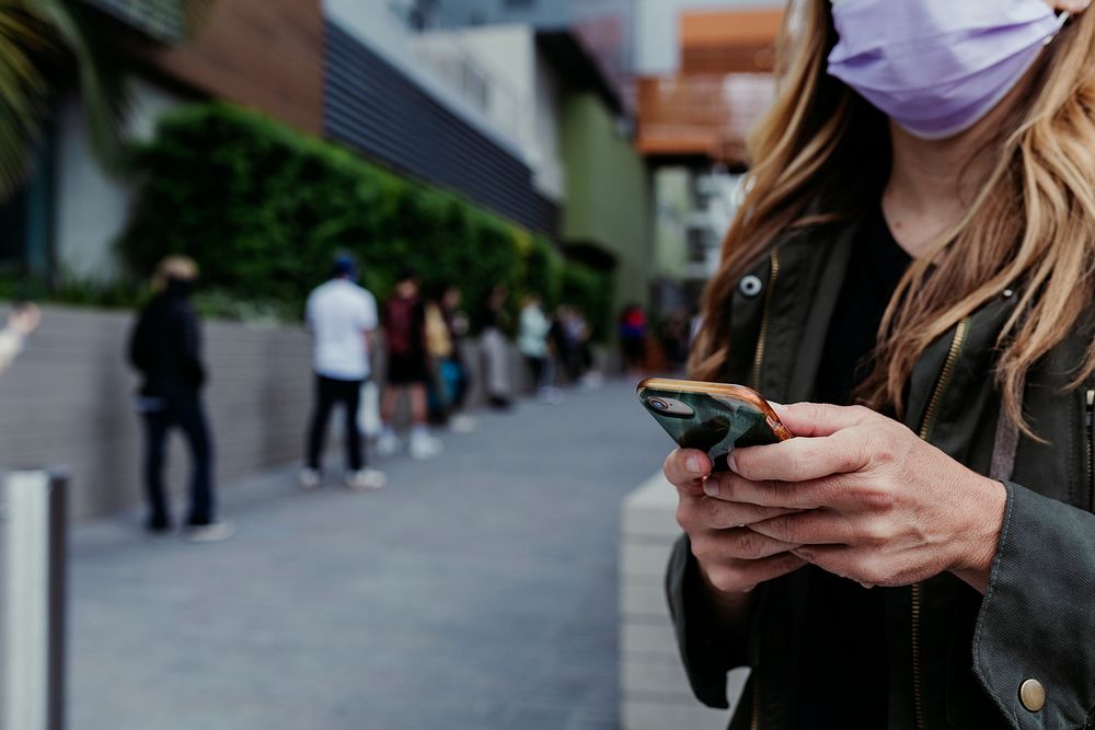 Woman with a face mask using a phone during coronavirus outbreak. Los Angeles, USA, April 4, 2020