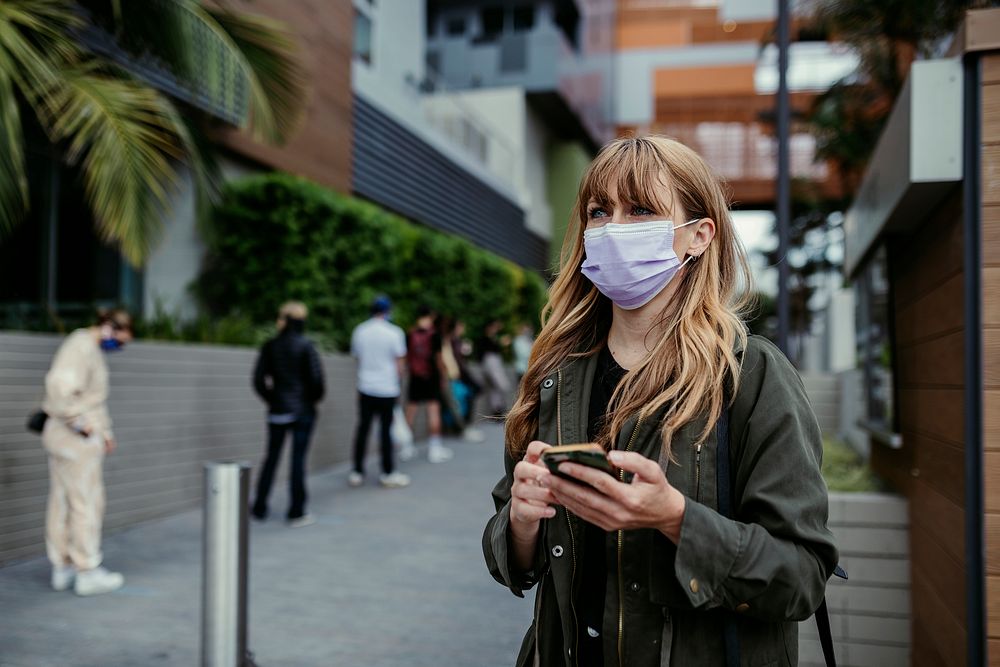 Woman with a face mask using a phone during coronavirus outbreak. Los Angeles, USA, April 4, 2020