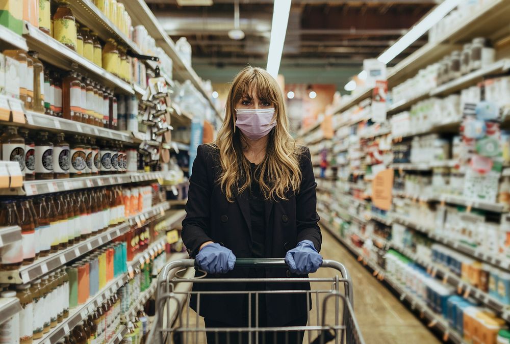 Woman in a face mask wearing latex gloves while shopping in a supermarket during coronavirus quarantine