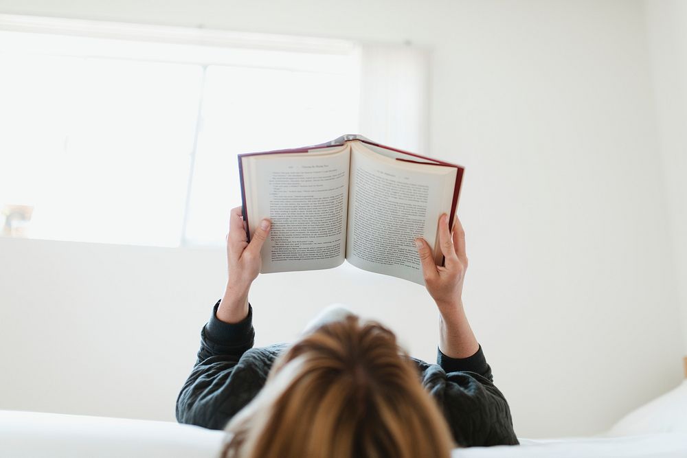 Woman reading a book on her bed during coronavirus quarantine