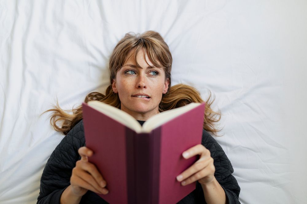 Woman reading a book on a bed during coronavirus quarantine