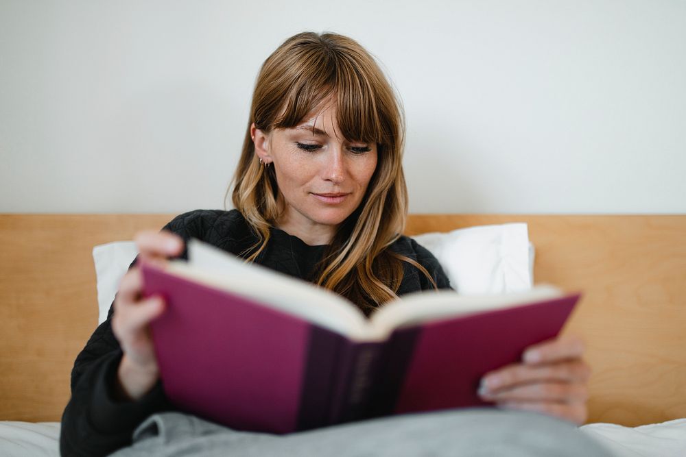 Woman reading a book in bed during coronavirus quarantine