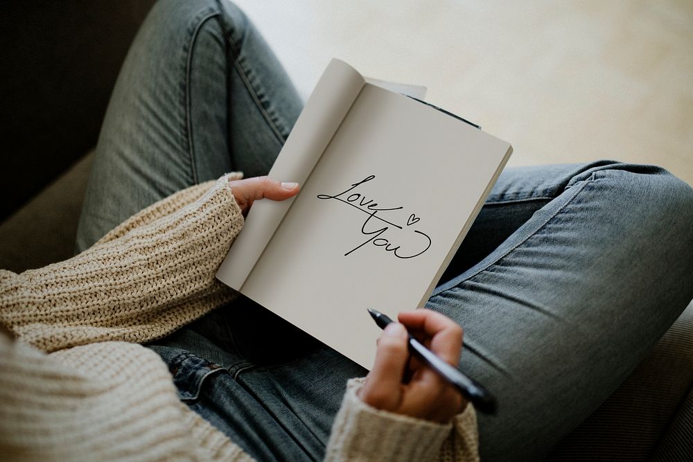 Woman writing love you in a notebook during quarantine