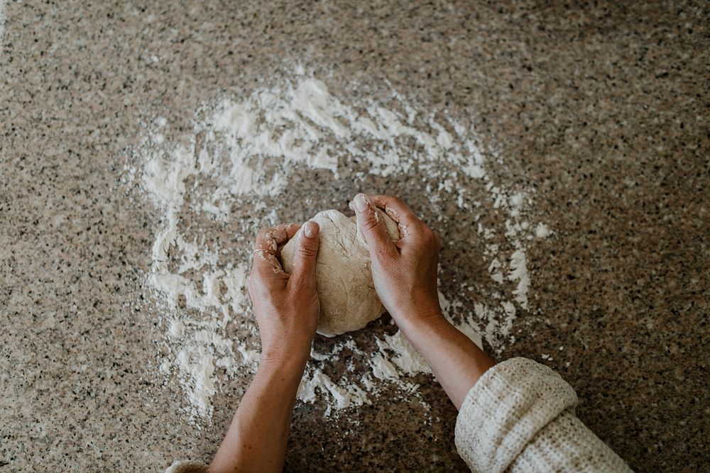 Woman kneading sourdough in her kitchen during quarantine
