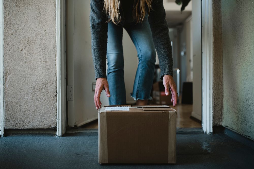 Woman getting her package from the front door during the coronavirus pandemic 