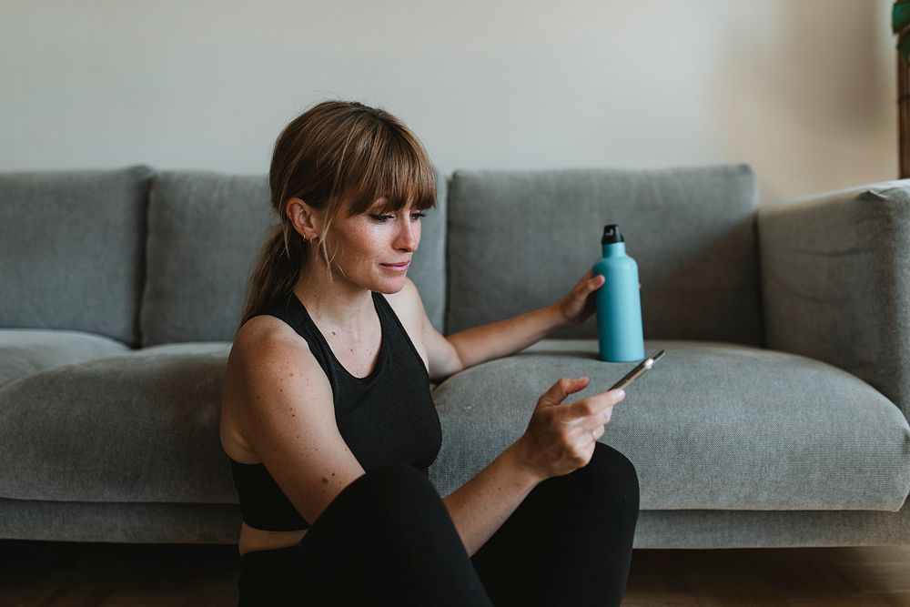 Woman in sportswear using her mobile phone during the coronavirus quarantine 