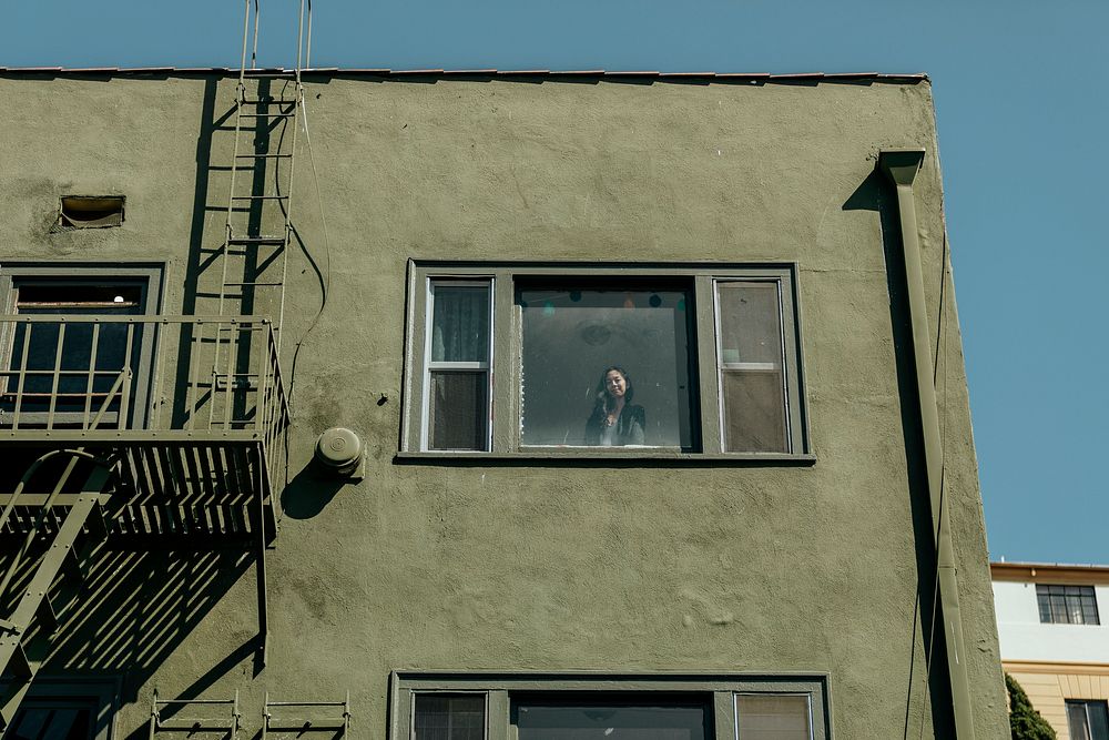 Woman looking out the window of her downtown LA apartment during the covid-19 pandemic