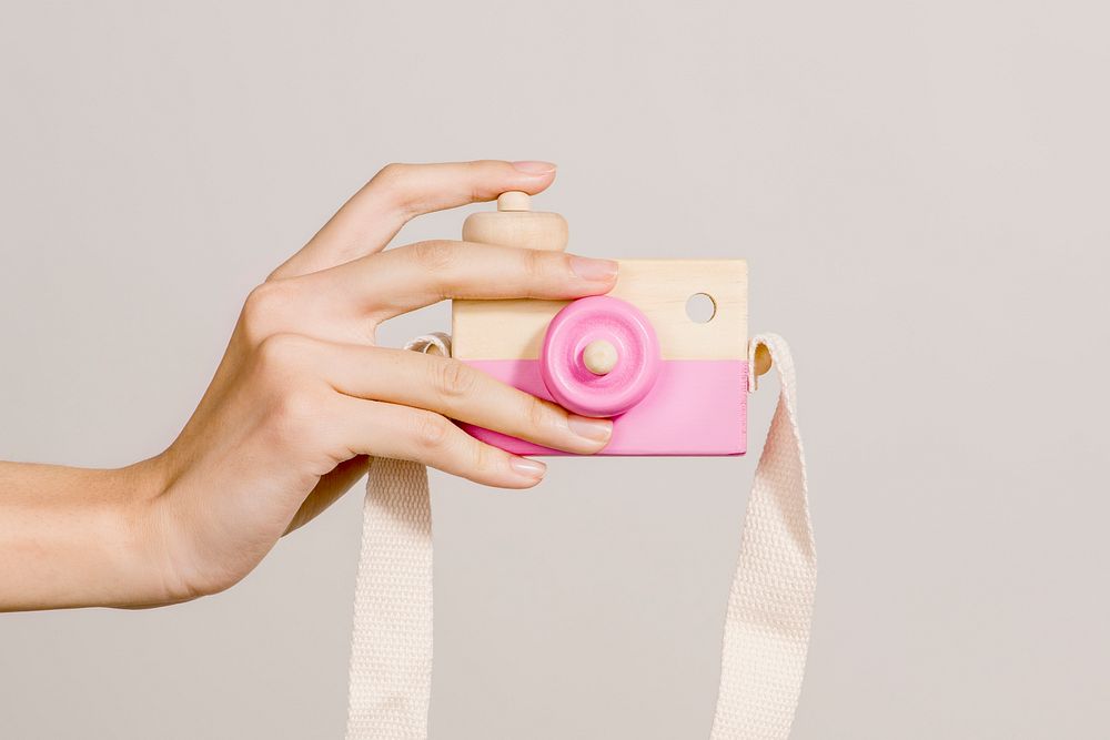 Woman with a pink wooden camera toy