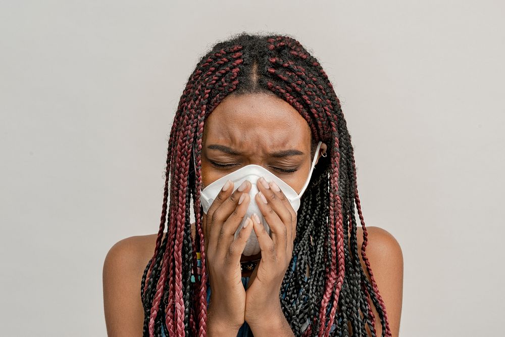 Black woman wearing a mask and coughing 