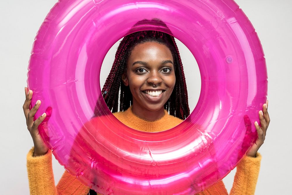 Cheerful black woman with a pink swim tube