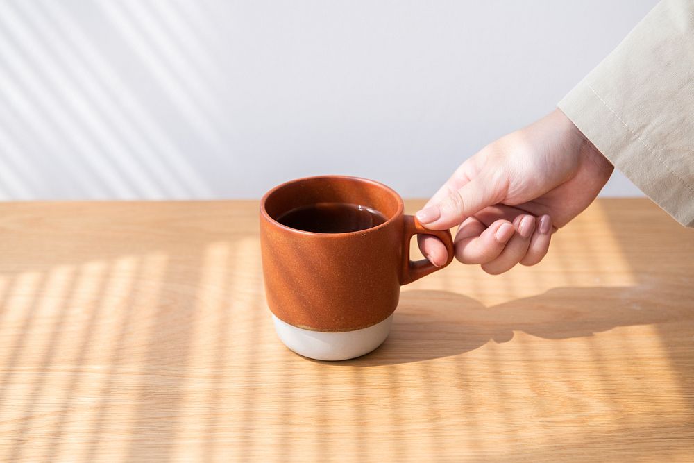 Woman getting a coffee cup from a wooden table