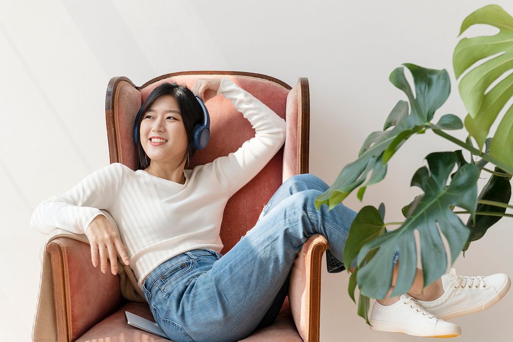 Asian woman listening to music on a red sofa