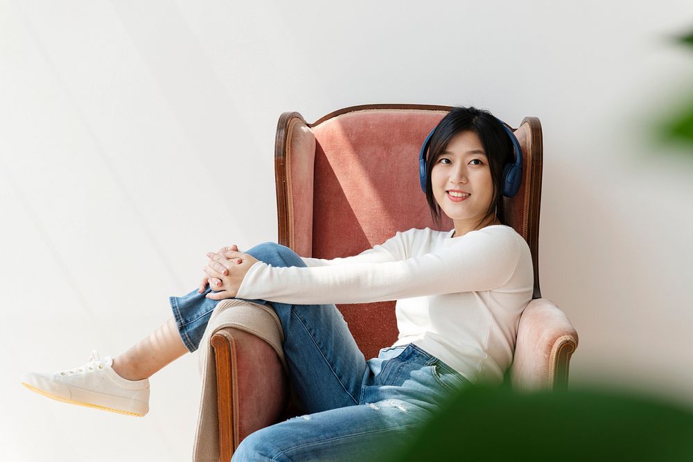 Asian woman listening to music on a red sofa