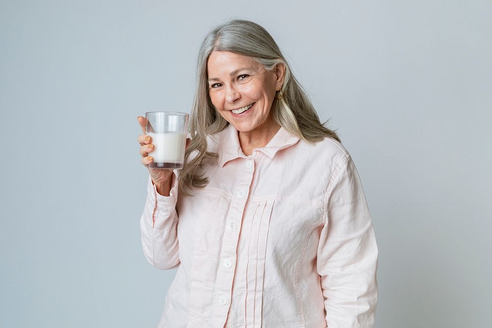 Cheerful senior woman drinking a glass of milk