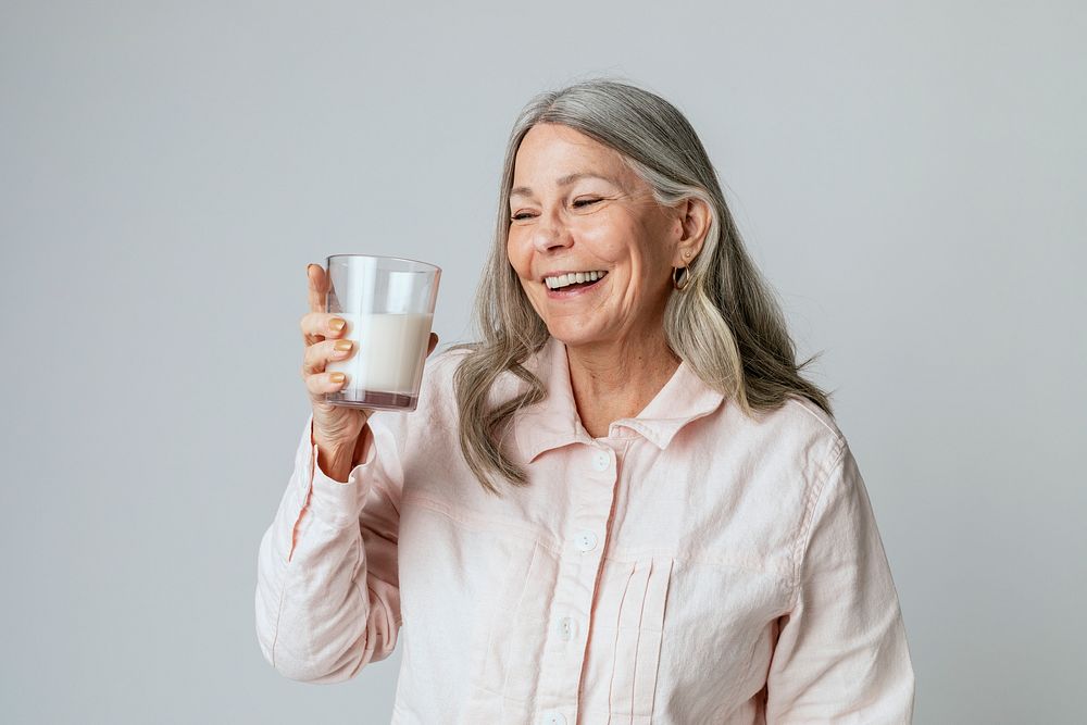 Cheerful senior woman drinking a glass of milk