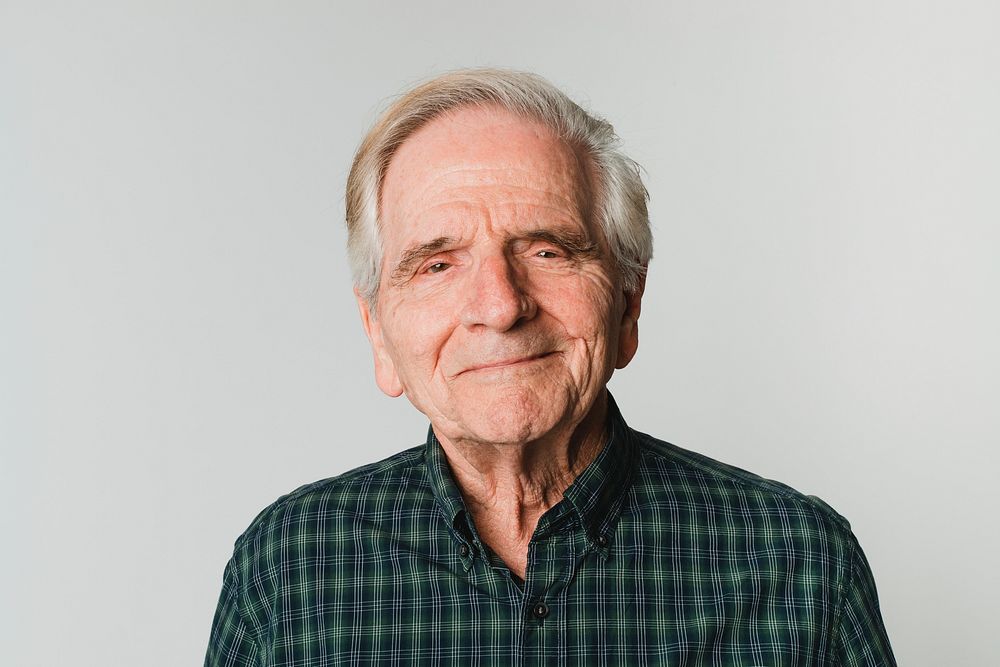 Elderly Caucasian man with white hair smiling on gray background