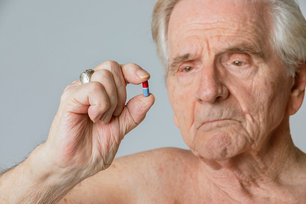 Senior man taking a capsule pill for viral disease