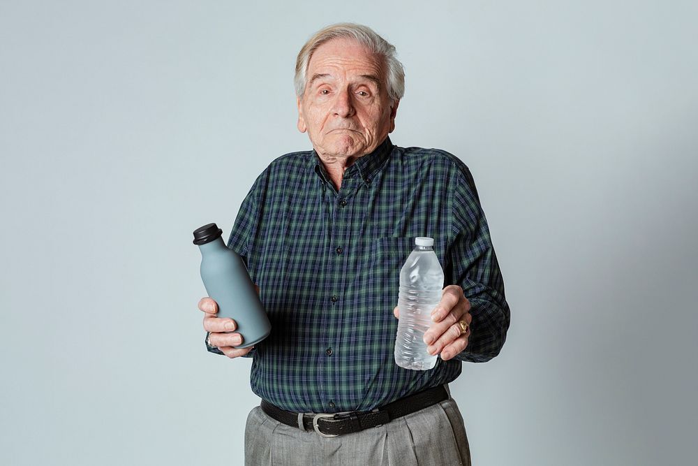 Puzzled senior man holding a reusable and a plastic water bottle 