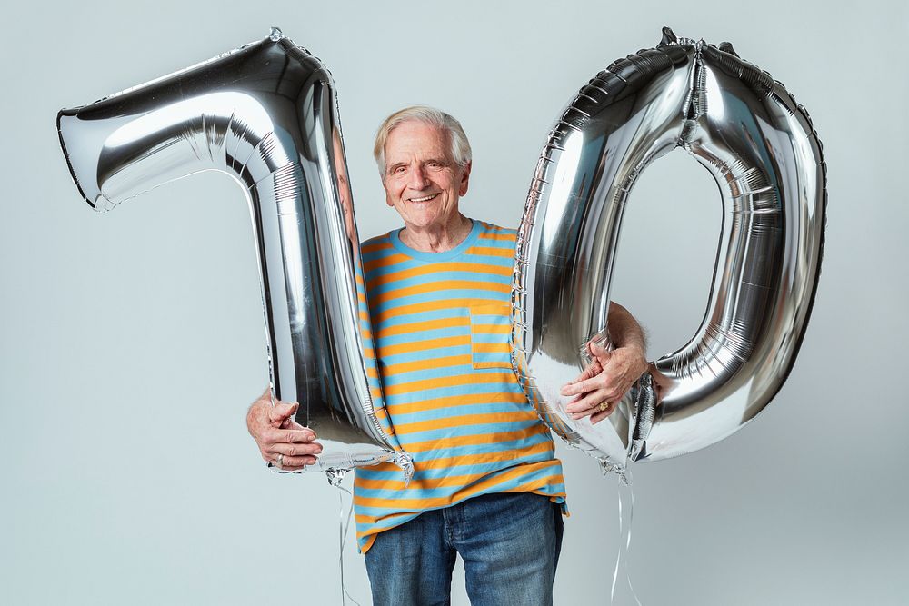 Senior man holding silver balloons for his 70th birthday celebration 