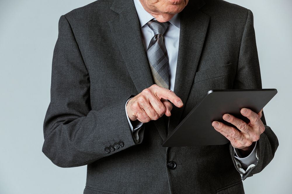 Senior businessman in a suit using a digital tablet