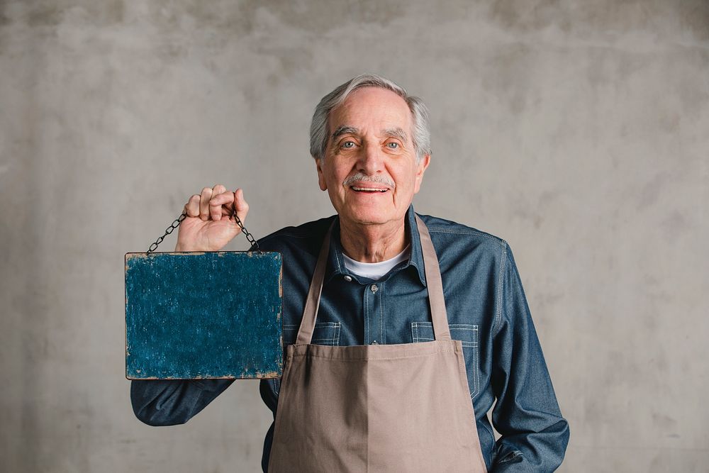 Senior man holding blank shop sign plate