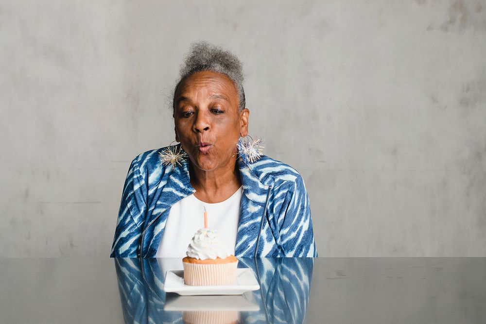 Senior woman blowing a candle on a cake on her birthday celebration