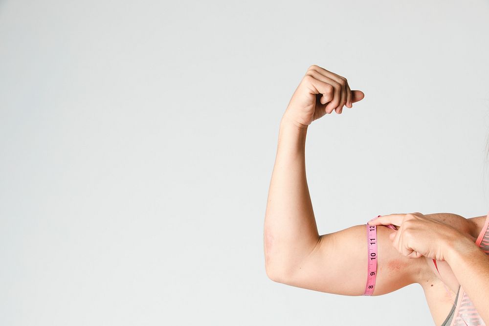 Female athlete measuring her biceps