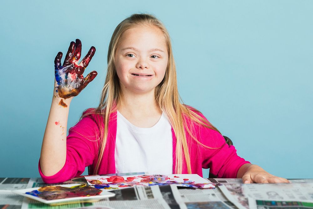 Cute girl with Down Syndrome playing with paints