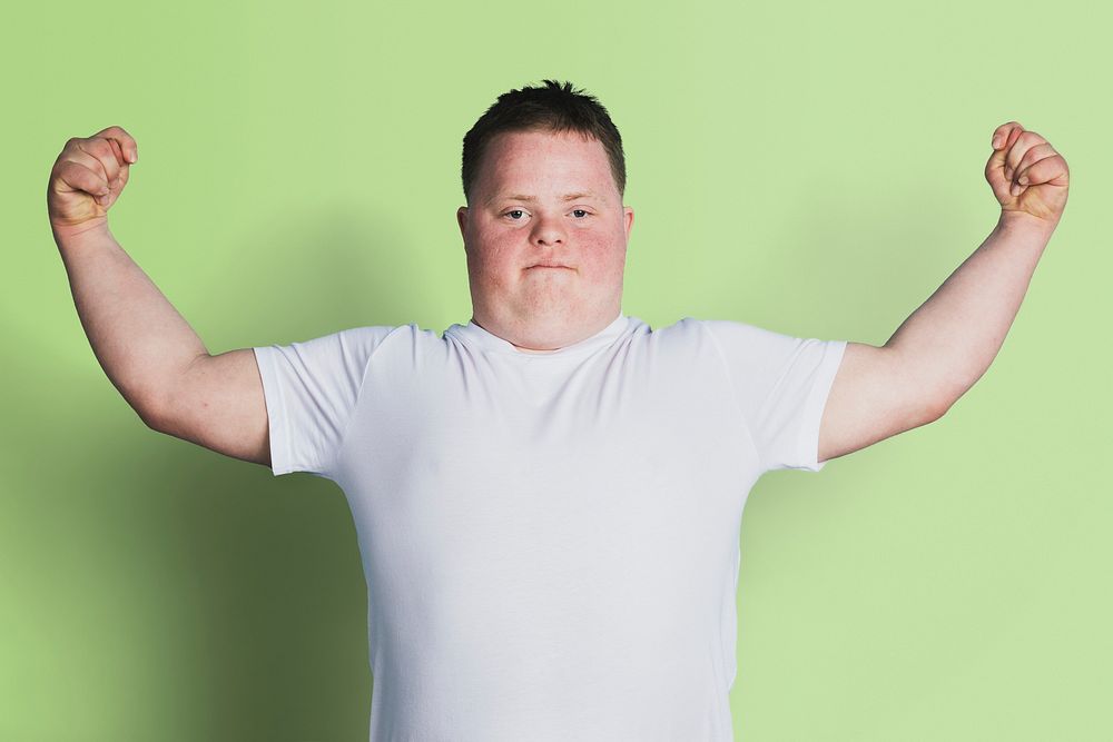 Proud boy with down syndrome flexing his arms 