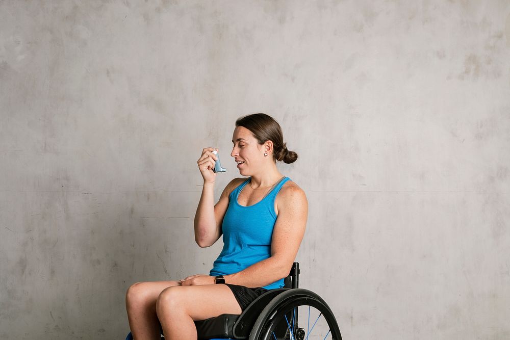 Woman in a wheelchair using an asthma inhaler