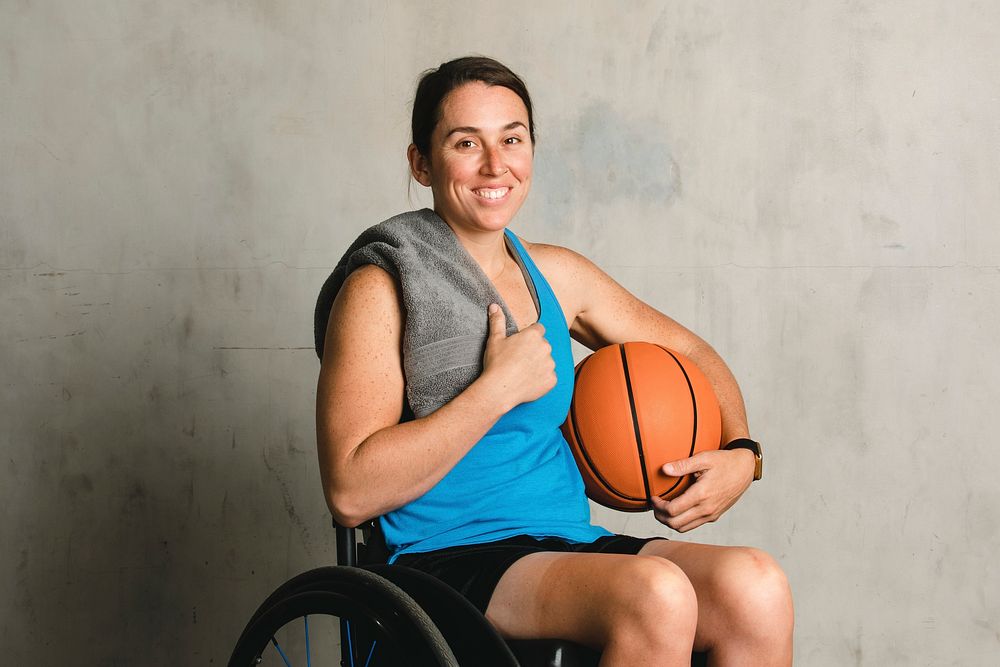 Happy female athlete in a wheelchair with a basketball