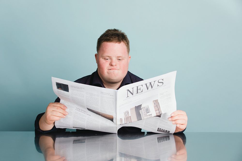 Boy with down syndrome reading a newspaper during the coronavirus pandemic