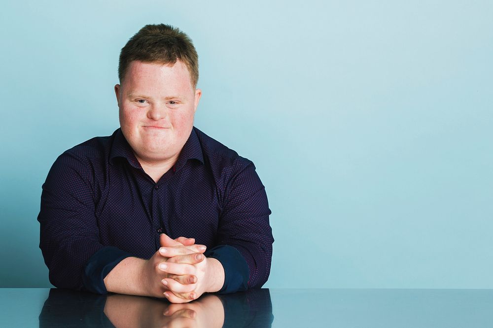 Confident boy with down syndrome sitting on a chair 