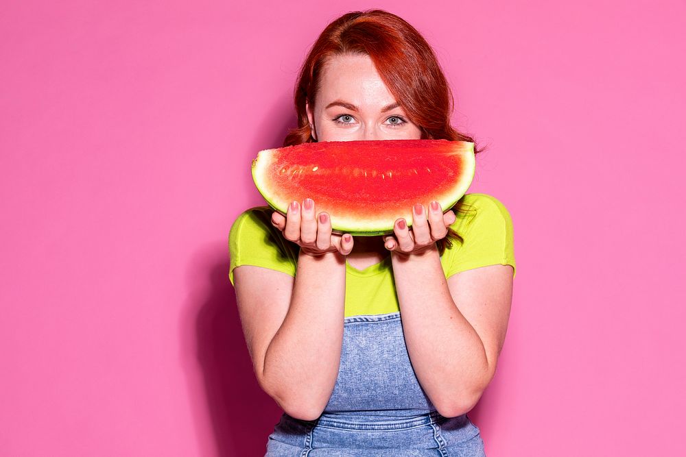 Woman holding a watermelon over her mouth
