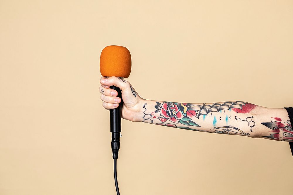 Hand with tattooed holding a microphone