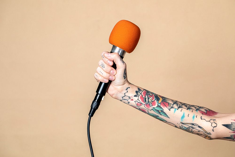 Tattooed feminine hand holding a microphone
