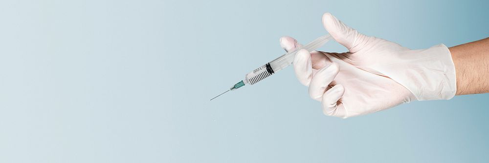 Hand wearing a white glove holding a syringe