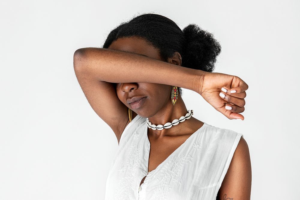 Unhappy black woman with arms over her face 