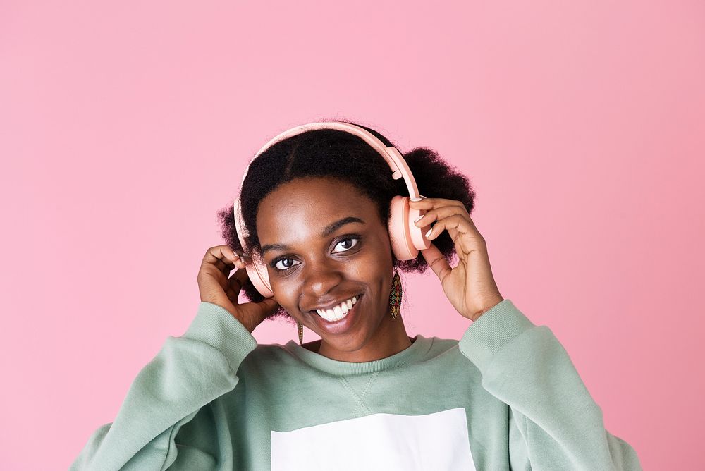 Black woman enjoying the music with pink background