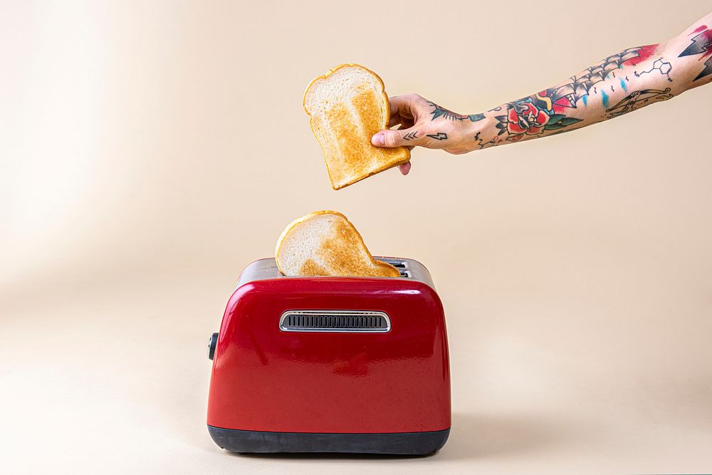 Hand holding bread popping up from a red toaster