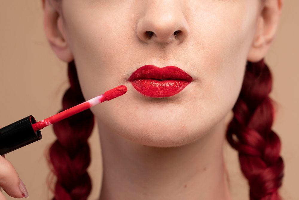 Closeup on beautiful woman applying a red lipstick