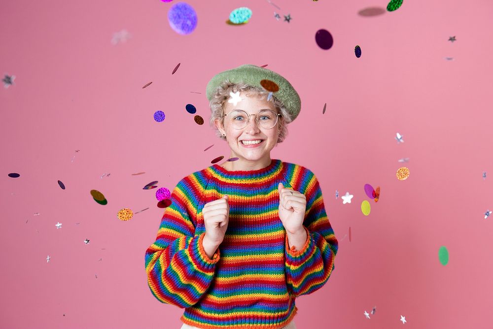 Studio portrait of a girl wearing glasses in a confetti in a pink background