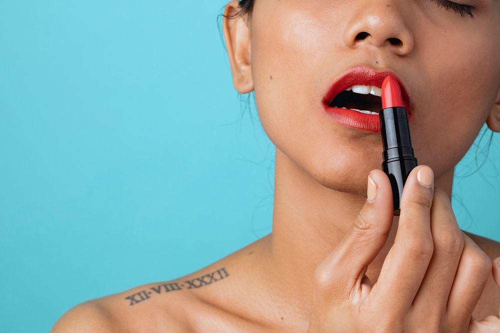 Closeup of a beautiful woman applying a lipstick