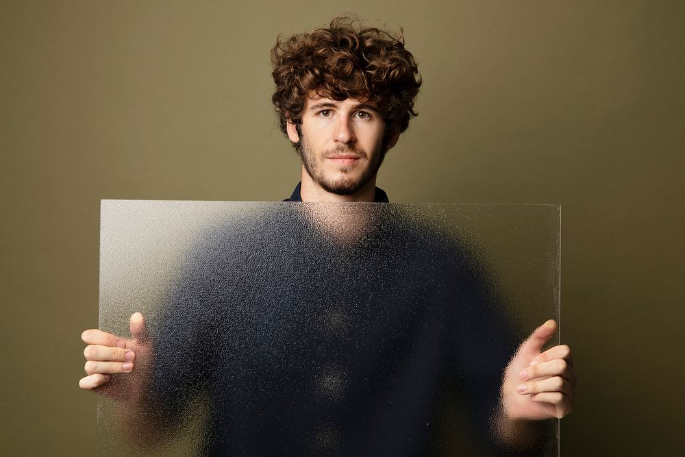 Man holding a translucent glass by the wall