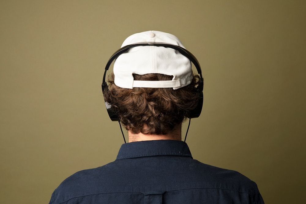 Rear view of a man in white cap listening to music using headphones